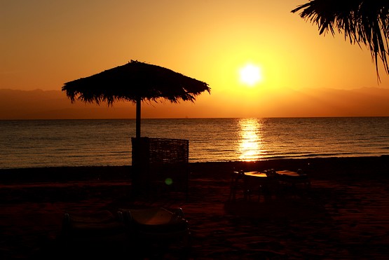 Красивый восход солнца из-за гор Иордании отснят с пляжа в Египте у Красного моря