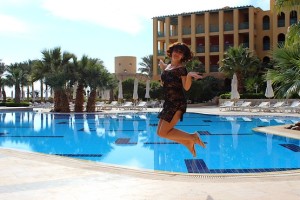 Танюшка в полёте на фоне бассейна, пальм и отеля в Египте